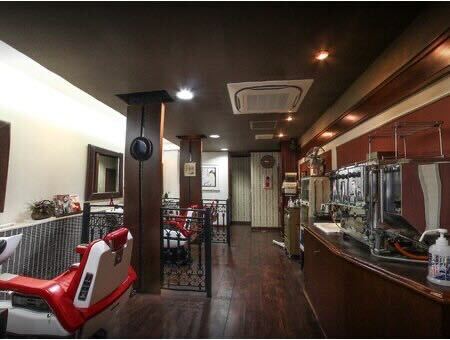 施術スペース - 赤いバーバーチェアとダークウッドの内装